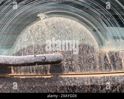 Cremona, Italie - 9 juin 2024 pare-brise rétro de voiture noir poussiéreux dans la ville a besoin d'être nettoyé, ressemblant à une tempête de sable du désert avec gris, brun et blanc Banque D'Images