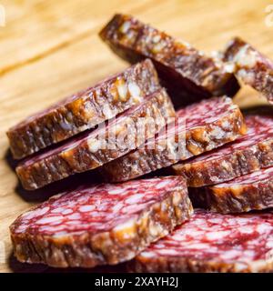 Gros plan sur la viande du traiteur. Salami tranché avec graisse visible, parfait pour le contenu culinaire. Banque D'Images