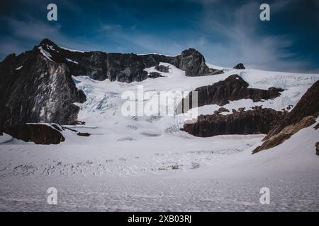 Une vue imprenable sur un glacier de l'Alaska, mettant en valeur les majestueuses formations de glace et le terrain accidenté sous un ciel bleu clair. Cette image capture le b brut Banque D'Images