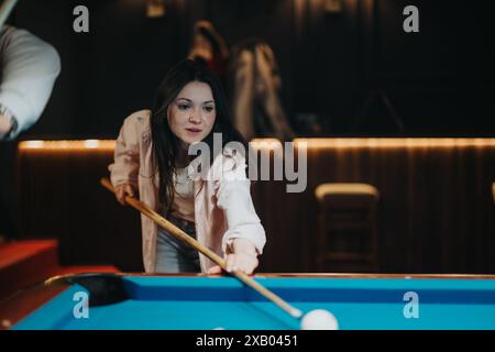 Les amis profitent d'une soirée amusante en jouant au billard dans un bar confortable Banque D'Images