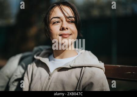 Jeune fille insouciante souriant tout en profitant du soleil dans un parc le week-end Banque D'Images