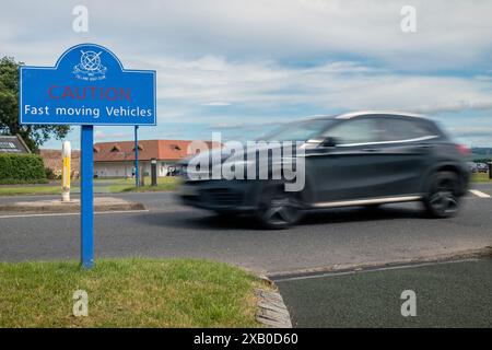 Panneau d'avertissement de véhicules rapides avec passage de voiture flou - Gullane, East Lothian, Écosse, Royaume-Uni. Banque D'Images