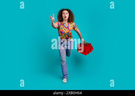 Photo de Crazy gentil femme drôle porter des vêtements imprimés élégants porter des sacs dépêche le centre de magasin isolé sur fond de couleur cyan Banque D'Images