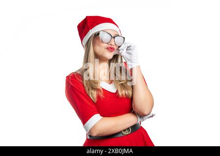 Jeune femme habillée en Père Noël avec des lunettes faisant un geste de baiser isolé sur fond blanc Banque D'Images