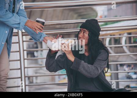 Femme aidant les mains aux sans-abri pauvreté mendiant homme tenant la main demandant l'argent travail et espérant de l'aide dans la ville sale impuissante assis dans les rues Banque D'Images