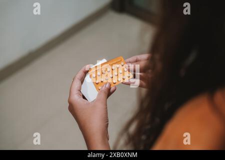 Vue arrière des mains d'une jeune femme tenant un paquet de pilules contraceptives. Banque D'Images