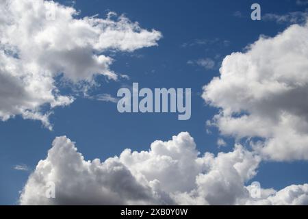 Ciel bleu principalement rempli de nuages blancs moelleux. Les nuages sont de formes et de tailles diverses, mis en évidence par une couleur bleu plus foncé qui les aide à se mettre en valeur Banque D'Images