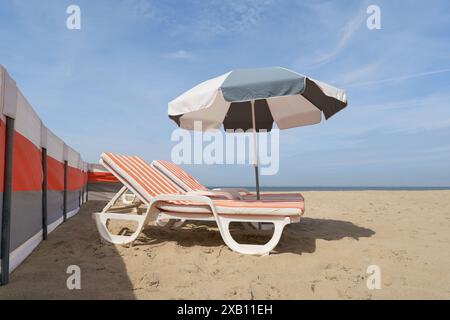 Parasol et chaise longue sur la plage de la mer du Nord près de Haan en Flandre occidentale, Belgique Banque D'Images