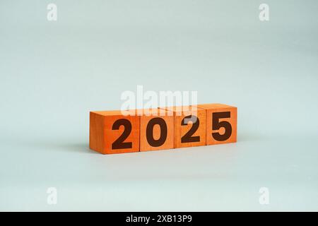 Cubes en bois avec les numéros 2025 sur une table sur un fond blanc. Planification des activités en 2025 Banque D'Images