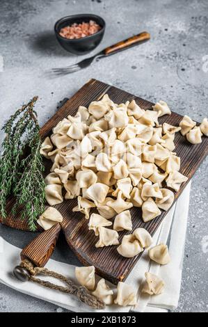 Manti non cuite Dumpling sur bois avec herbes, nourriture crue. Arrière-plan gris. Vue de dessus. Banque D'Images