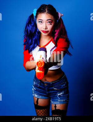 Femme asiatique Harley Quinn Cosplay Studio regardant la caméra 3/4 longueur Banque D'Images