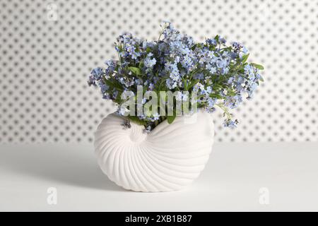 Bouquet de belles fleurs oublie-me-pas dans un vase sur une table blanche Banque D'Images