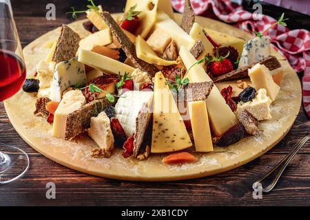 Assiette de fromage préparée avec des fromages de luxe et du vin sur une table en bois Banque D'Images