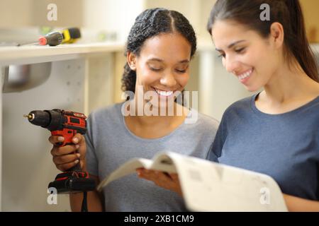 Multi ethnique heureux colocataires vérifiant le manuel d'installation de meubles déménagement maison Banque D'Images