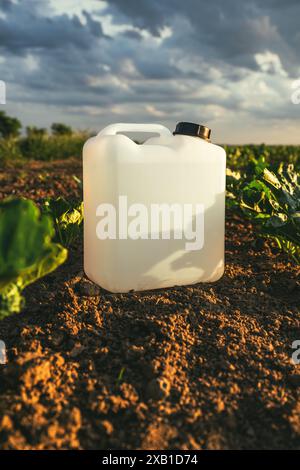 Récipient blanc blanc vierge de boîte d'herbicide dans le champ de semis de betterave à sucre au coucher du soleil au printemps, foyer sélectif Banque D'Images