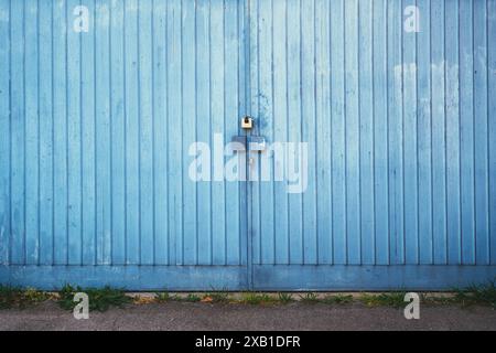 Porte de garage métallique bleue verrouillée avec cadenas comme arrière-plan Banque D'Images