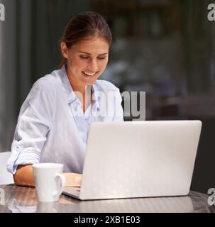 Femme d'affaires, ordinateur portable et café dans le restaurant professionnel, freelance et travaillant à l'extérieur. Personne féminine, heureuse et souriante avec ordinateur ou dactylographie Banque D'Images