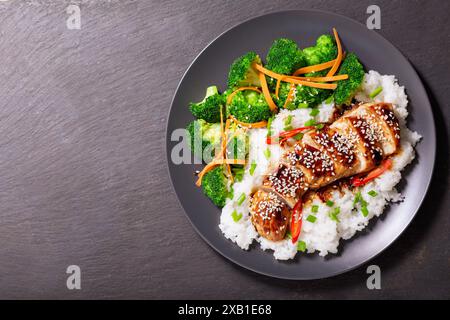 Assiette de poulet teriyaki avec légumes et riz sur fond sombre, vue de dessus Banque D'Images