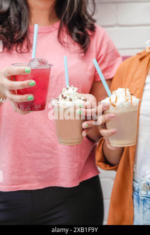 Les jeunes femelles tenant des boissons glacées frappent le café et la neige fondante à la main. Banque D'Images
