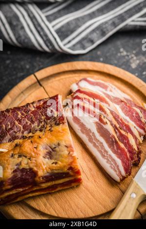 Gros plan de bacon fumé tranché sur une planche à découper en bois Banque D'Images