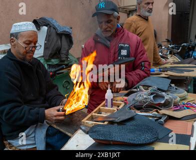 Marrakech, Maroc - 23 mars 2024 : cordonniers traditionnels dans le souk de la médina de Marrakech réparant des chaussures anciennes Banque D'Images