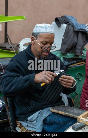 Marrakech, Maroc - 23 mars 2024 : cordonniers traditionnels dans le souk de la médina de Marrakech réparant des chaussures anciennes Banque D'Images