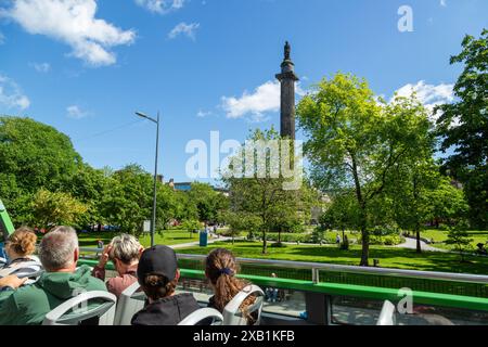 Un groupe de touristes sur un bus à toit ouvert passant St Andrew Square avec le monument Melville en son centre. Banque D'Images