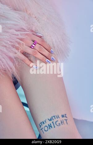 Gros plan sur la jambe des femmes, montrant une lecture de tatouage rester avec moi ce soir. La main de la femme est visible dans le coin supérieur gauche, portant un anneau rose et montrant la lumière b. Banque D'Images