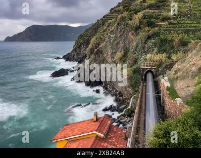 Long flou d'exposition du train passant par le tunnel à côté de la mer en Italie. Banque D'Images