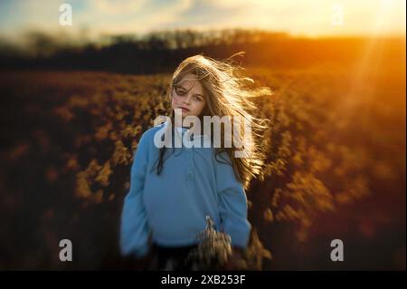 Belle jeune fille long cheveux blonds coulants dans le champ doré Banque D'Images