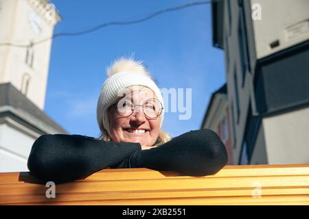 Femme plus âgée avec un chapeau blanc et des lunettes profitant d'une journée ensoleillée à l'extérieur Banque D'Images
