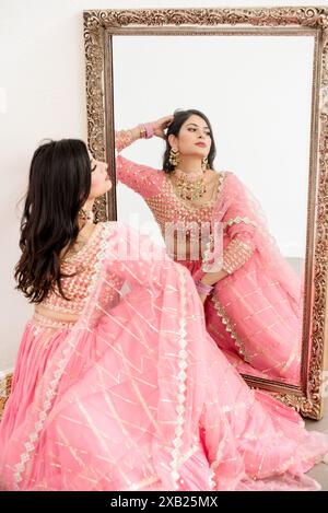 Reflet de femmes indiennes en miroir portant un traditionnel rose Banque D'Images