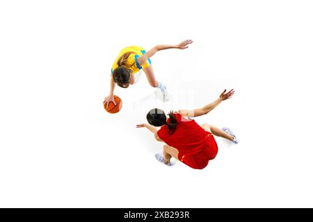 Vue aérienne de deux jeunes femmes, joueuses de basket-ball en uniforme rouge et jaune jouant isolé sur fond blanc de studio Banque D'Images