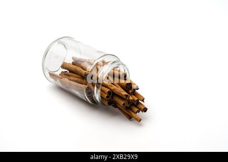 un pot en verre hors bâtons de cannelle, avec texture de détail renverser hors du récipient, isolé sur fond blanc, concept de stockage d'épices dans le kitc Banque D'Images