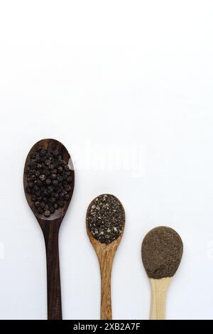 poivre noir entier, grossier et finement moulu sur cuillère en bois, isolé sur fond blanc Banque D'Images