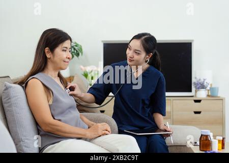 Infirmière effectuant un bilan de santé sur la femme senior à la maison, professionnel de la santé utilisant le stéthoscope, service de santé à domicile, réception de patient âgé Banque D'Images