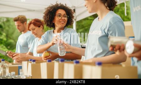 Groupe de volontaires préparant des rations alimentaires gratuites pour les pauvres dans le besoin. Les travailleurs caritatifs et les membres de la Communauté travaillent ensemble. Concept de don, d'aide humanitaire et de société. Banque D'Images