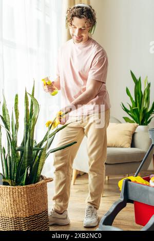 Un homme dans des plantes de nettoyage de vêtements de maison confortables. Banque D'Images