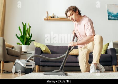 Un homme dans des vêtements de maison confortables aspire paisiblement un salon. Banque D'Images