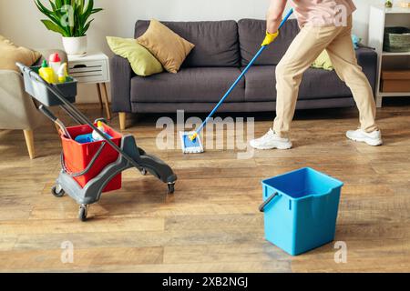 Un homme en action, nettoyant le sol avec une vadrouille dans un cadre confortable à la maison. Banque D'Images