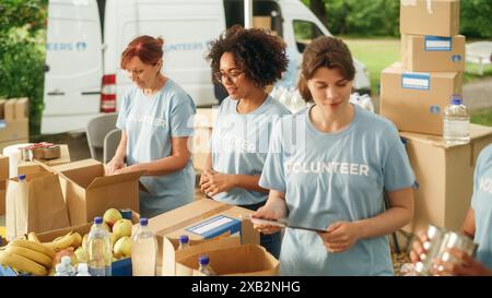 Groupe de volontaires préparant des rations alimentaires gratuites pour les pauvres dans le besoin. Les travailleurs caritatifs et les membres de la Communauté travaillent ensemble. Concept de don, d'aide humanitaire et de société. Banque D'Images