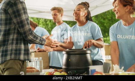 Groupe positif de jeunes volontaires adultes servant de la nourriture gratuite pour les pauvres dans le besoin. Les travailleurs caritatifs aident les membres de la communauté. Aide humanitaire aux réfugiés et aux immigrants. Banque D'Images