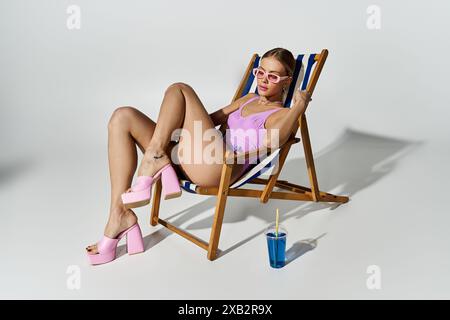 Femme blonde en maillot de bain se prélassant sur une chaise longue à talons hauts. Banque D'Images
