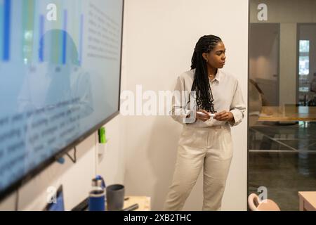 Une femme professionnelle focalisée présente des données sur un écran dans un environnement de coworking collaboratif Banque D'Images