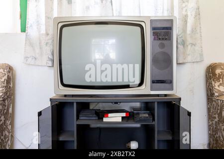 Un téléviseur à l'ancienne avec cadrans et haut-parleur sur un stand, mettant en valeur une ambiance de salon d'antan. Banque D'Images