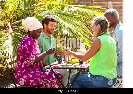 Groupe diversifié profitant d'un petit-déjeuner décontracté réunion en plein air entouré d'illustrations de la nature vibrante en été Banque D'Images