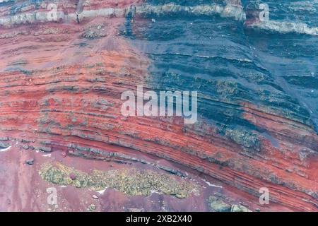 Vue des couches de sable rouge et noir vif dans une région montagneuse, mettant en valeur des motifs naturels complexes et des textures Banque D'Images