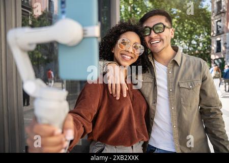 Un Chinois souriant et une femme hispanique prennent un selfie à Madrid, en Espagne. Le couple, habillé de façon décontractée, profite d'une journée ensoleillée dans la ville, capturant le Banque D'Images