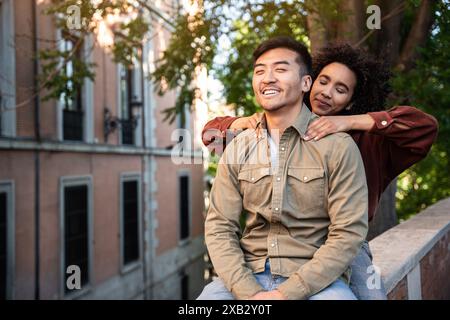 Un couple multiethnique composé d’un Chinois et d’une femme hispanique profite d’un massage par une journée ensoleillée à Madrid, en Espagne. Ils sont assis près, smi Banque D'Images