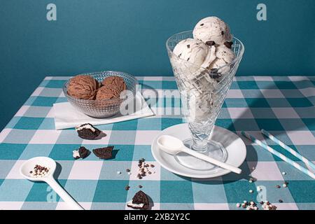 Élégant verre rempli de biscuits et de crème glacée, accompagné d'un bol de cuillères à chocolat, serti sur une nappe à carreaux bleue avec co dispersés Banque D'Images